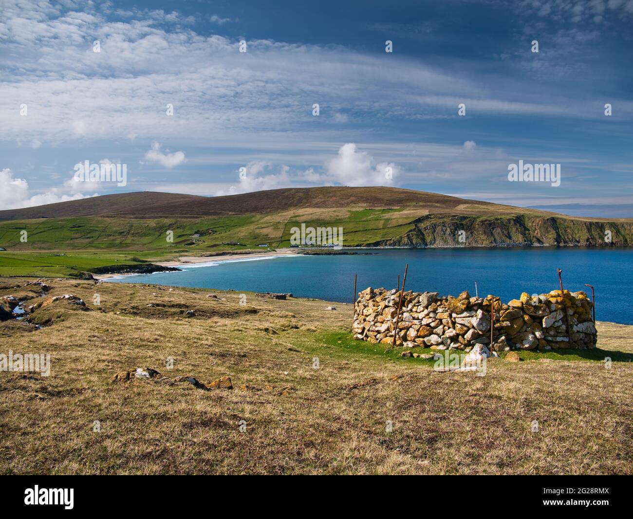 Mit Sonnenschein auf türkisfarbenem Wasser und einem alten Steingehege (ein Planticrub) auf der rechten Seite, der unberührte, verlassene Norwick Strand in Shetland. Stockfoto