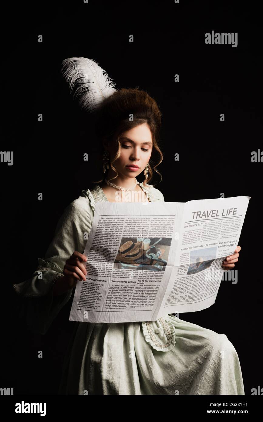 Charmante Frau im Retro-Outfit lesen Reise Leben Zeitung isoliert auf schwarz Stockfoto
