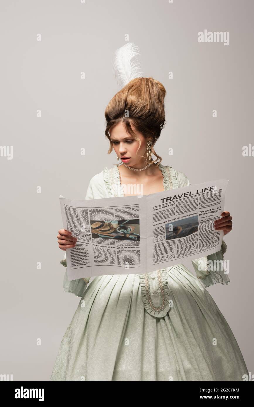 Besorgt Frau in eleganten Retro-Kleid Lesen Reise Leben Zeitung isoliert auf grau Stockfoto