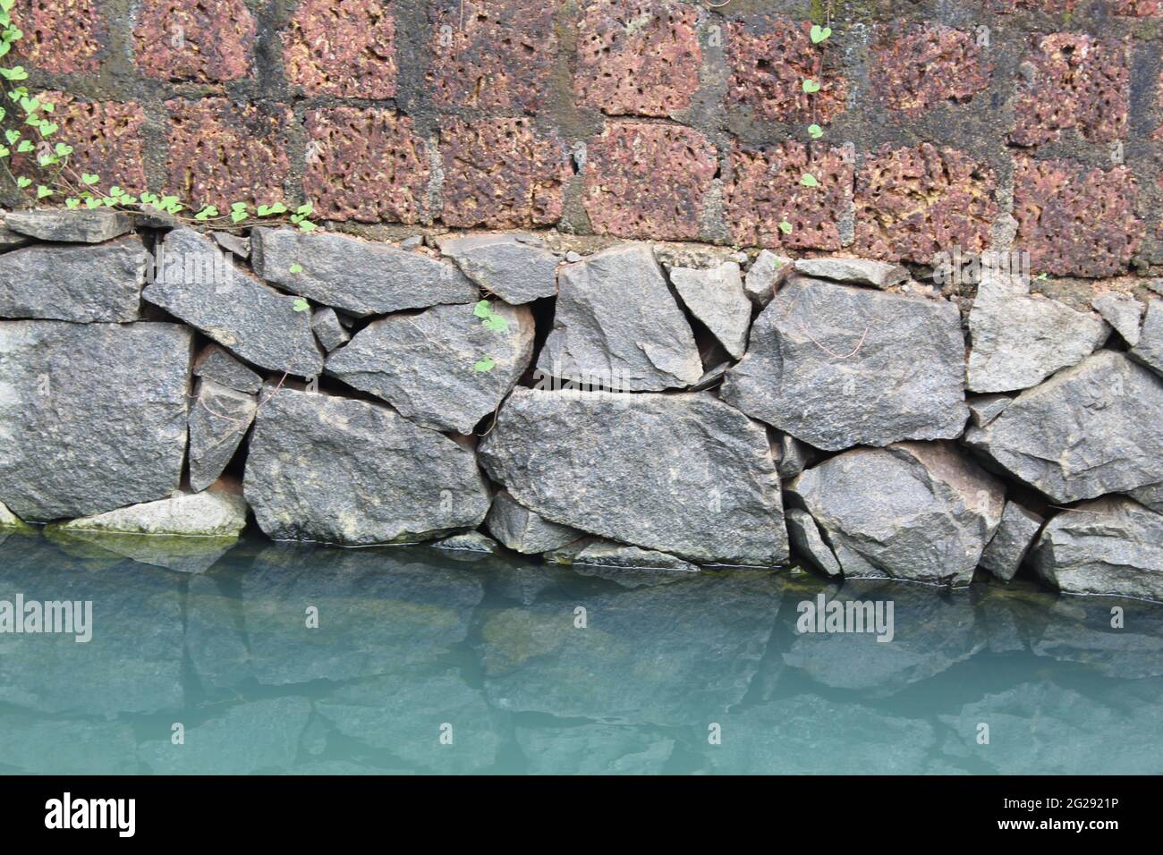 Wandfundamente in einem See aus schweren Steinen Stockfoto