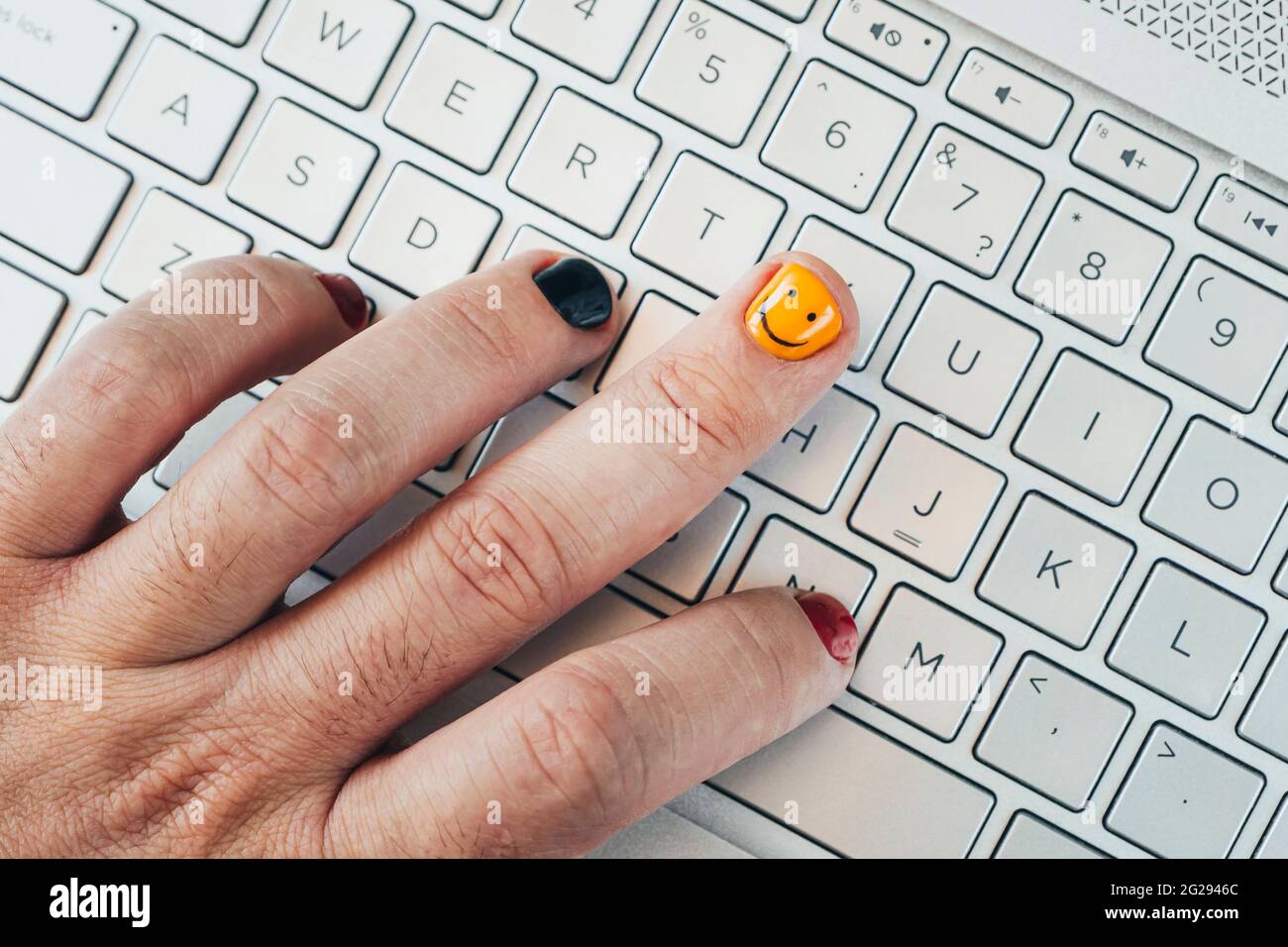 Ein junger Programmierer arbeitet an einem Computer. Lackierte Nägel aus der Nähe. Modisch lackierte Nägel an der Hand eines Mannes. Maniküre für Herren Stockfoto