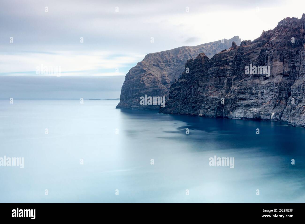 Langzeitbelichtung, Klippen von Los Gigantes ragen vor Sonnenaufgang in einen seidig glatten Atlantik, Teneriffa, Kanarische Inseln, Spanien Stockfoto