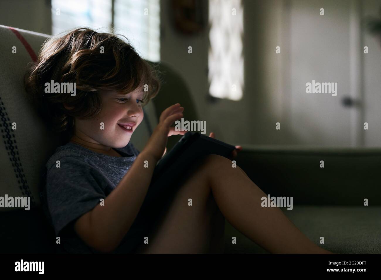 Junge lächelt, während Sie zu Hause ein digitales Tablet verwenden Stockfoto