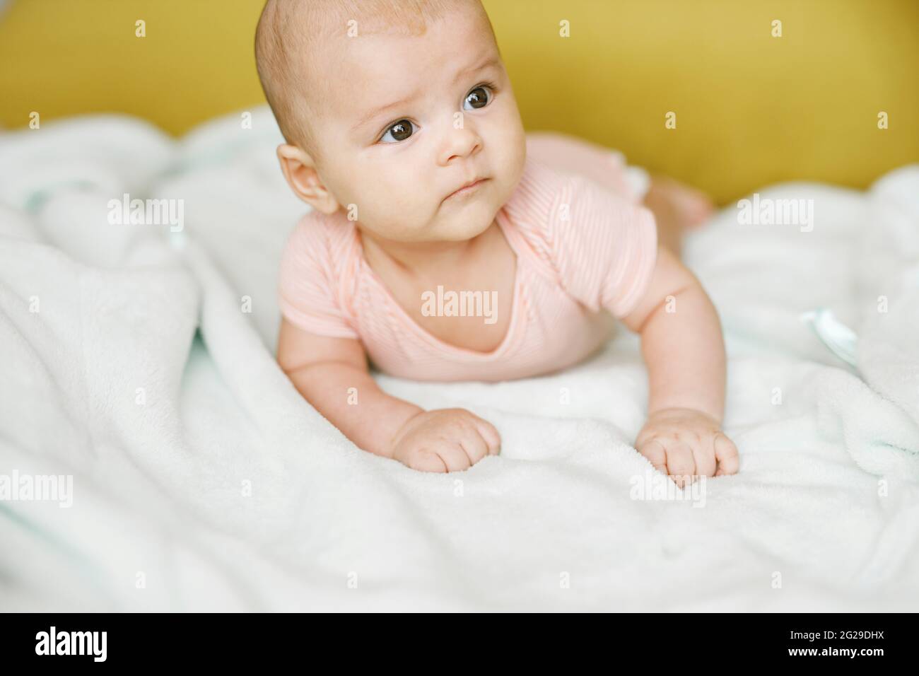 Entzückendes Baby im sonnigen Schlafzimmer. Das neugeborene Baby ruht in einer warmen, weichen Bettdecke. Lächelndes Kind, das die Kamera anschaut. Stockfoto