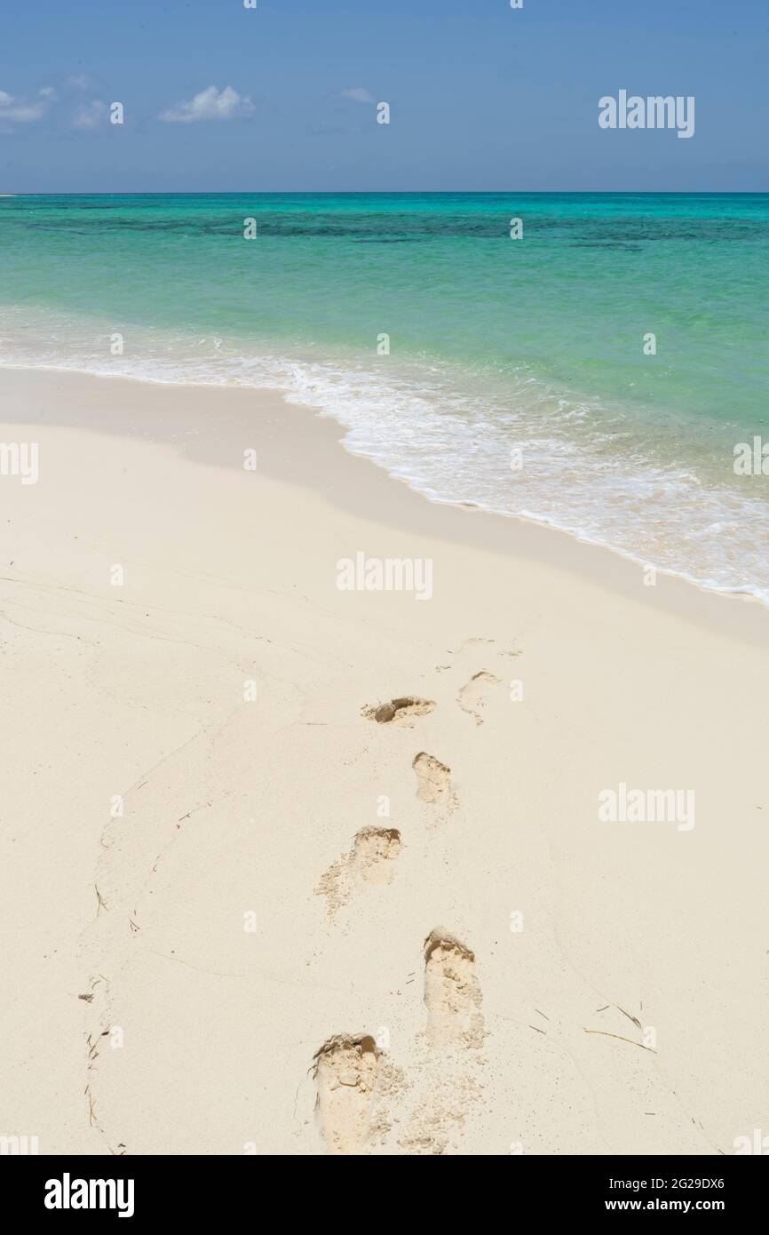Ein einsamer tropischer Strand mit menschlichen Fußabdrücken auf dem Sand Stockfoto
