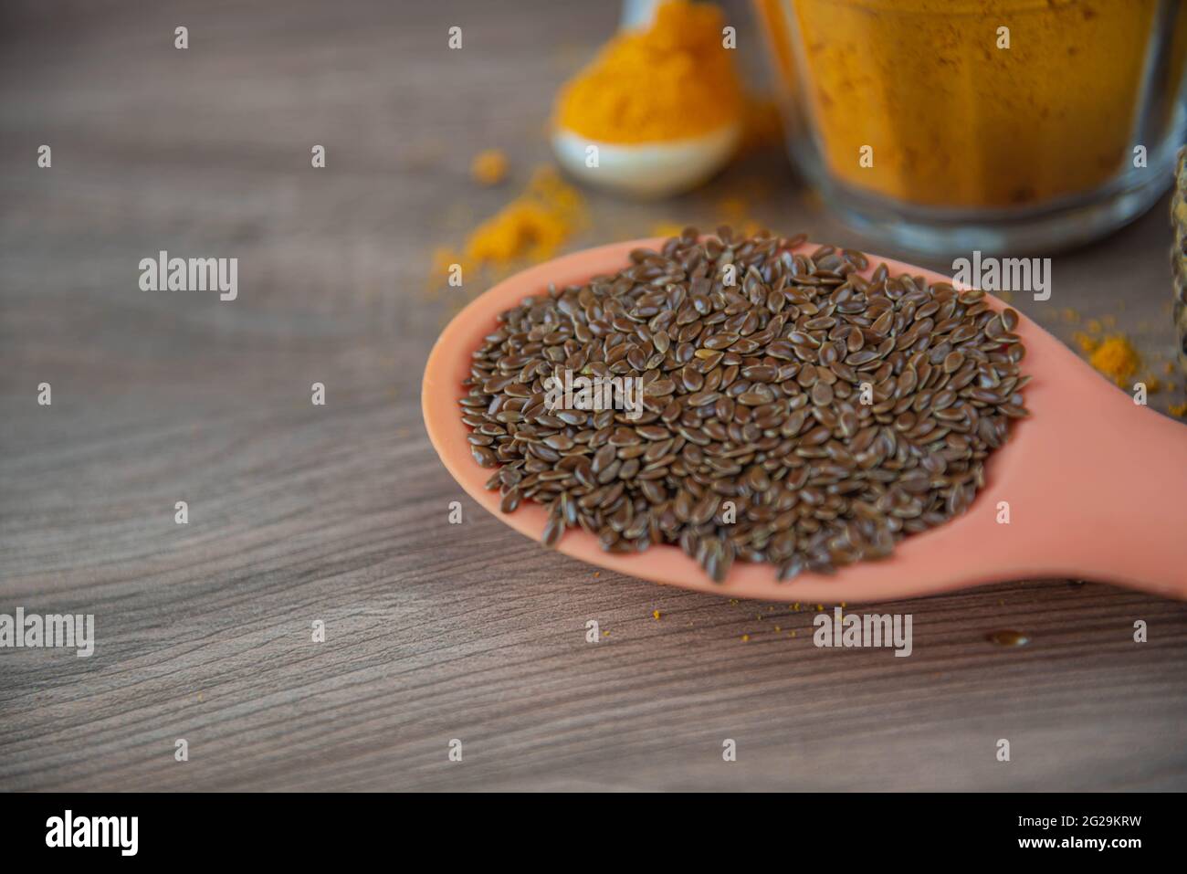 Leinsamen in Silikonlöffel auf Holzhintergrund. Leinsamen ist der Samen von Leinsamen (Linum usitatissimum) und wird beim Kochen verwendet. Gewürze und Gewürze. Stockfoto