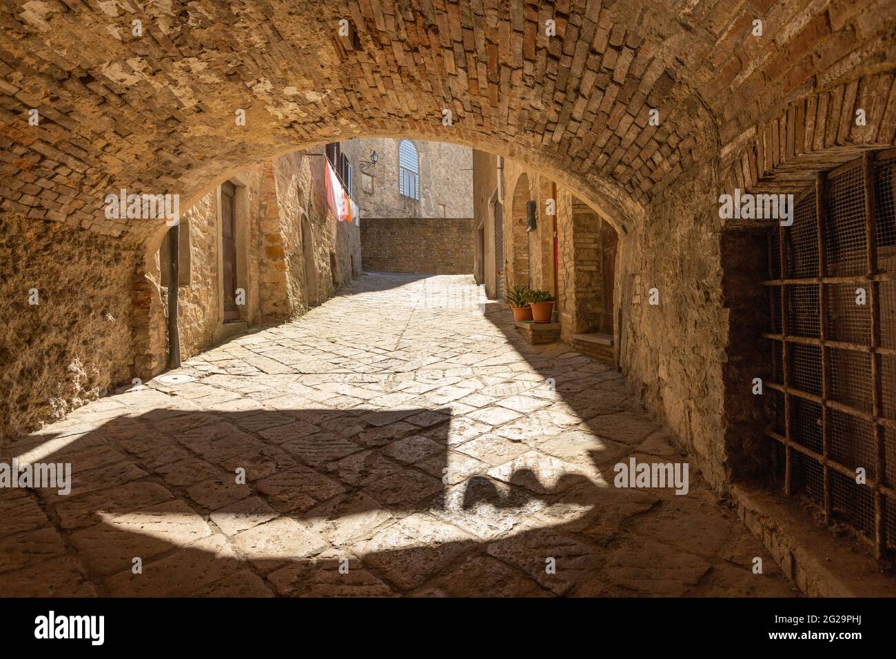 Gasse in der alten mittelalterlichen Stadt Volterra in der Toskana, Italien. Kleidung an Wäscheleinen. Stockfoto