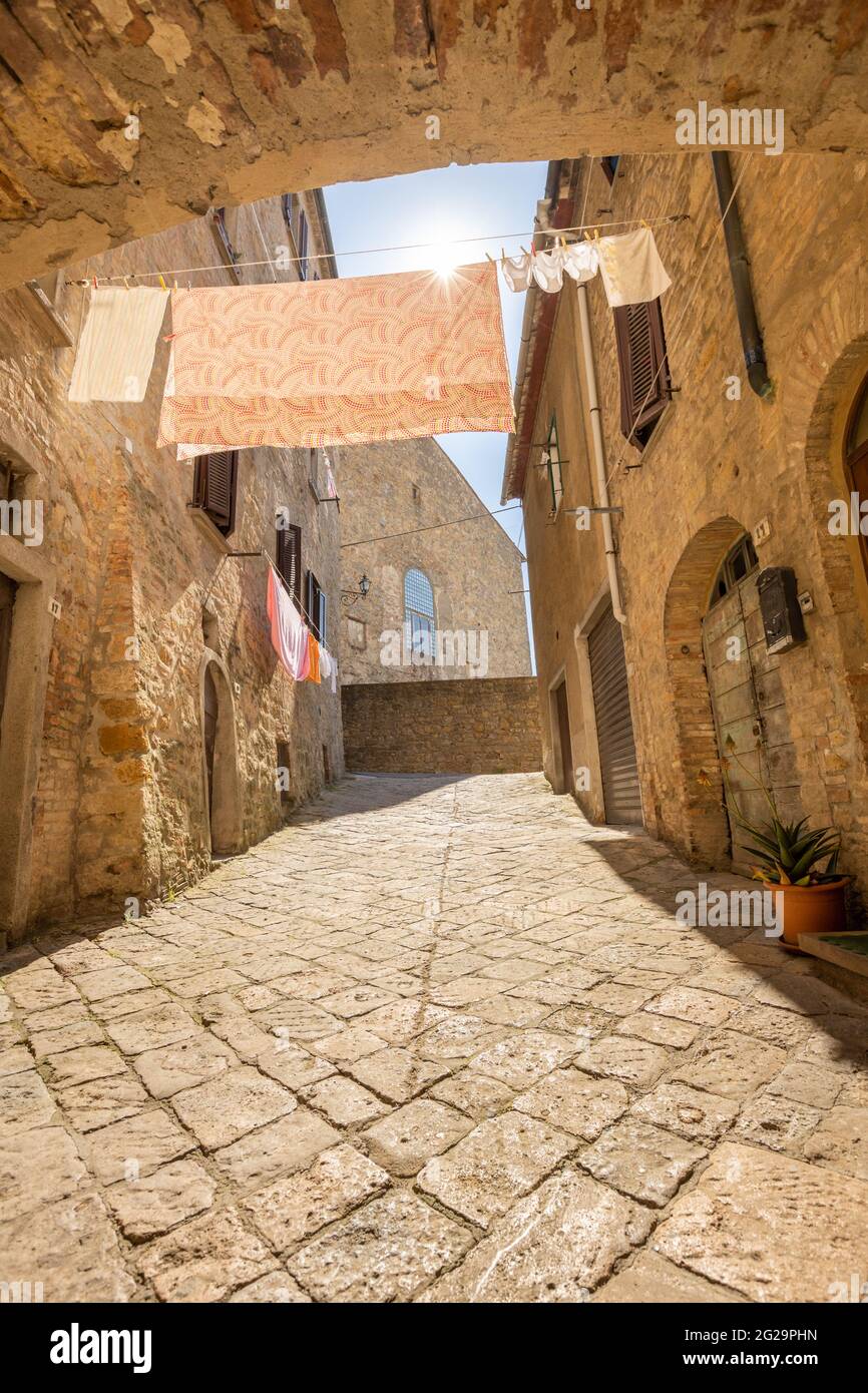 Gasse in der alten mittelalterlichen Stadt Volterra in der Toskana, Italien. Kleidung an Wäscheleinen. Stockfoto