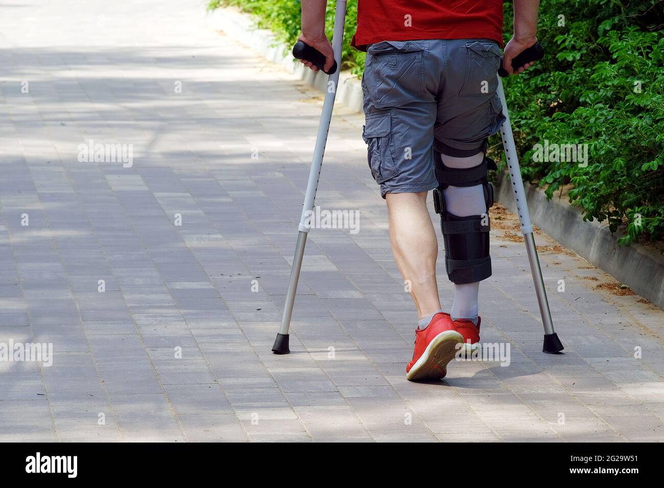 Verletzung des Bewegungsapparates. Sportverletzung. Befestigung der Fußgewölbestütze am Bein. Der Mann hat Krücken in den Händen Stockfoto