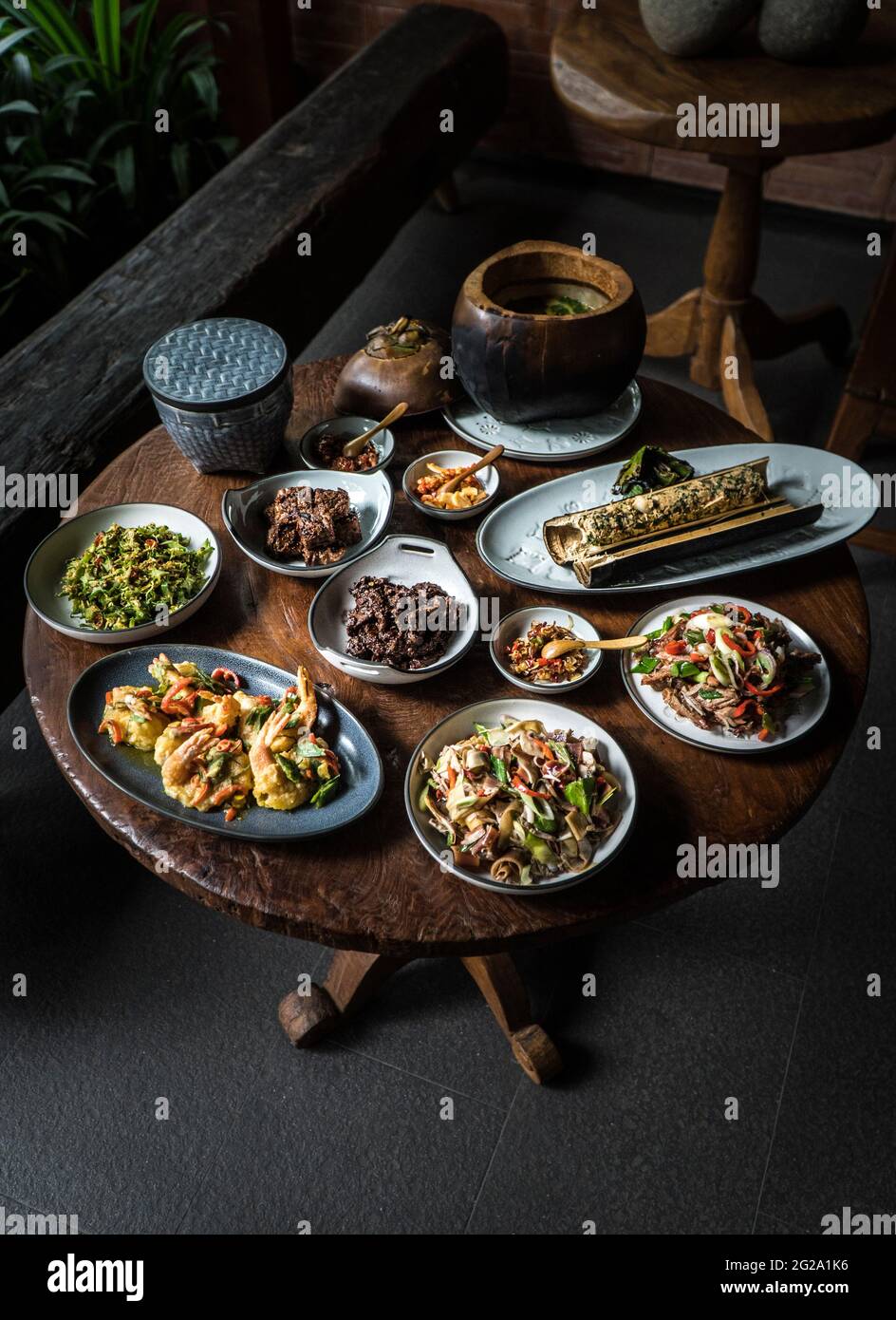 Von oben serviert runden Holztisch mit verschiedenen Appetit Gerichte der Mischung aus tropischen Früchten und Gemüse in Zusammensetzung mit Meeresfrüchten und Kräutern vor Stockfoto