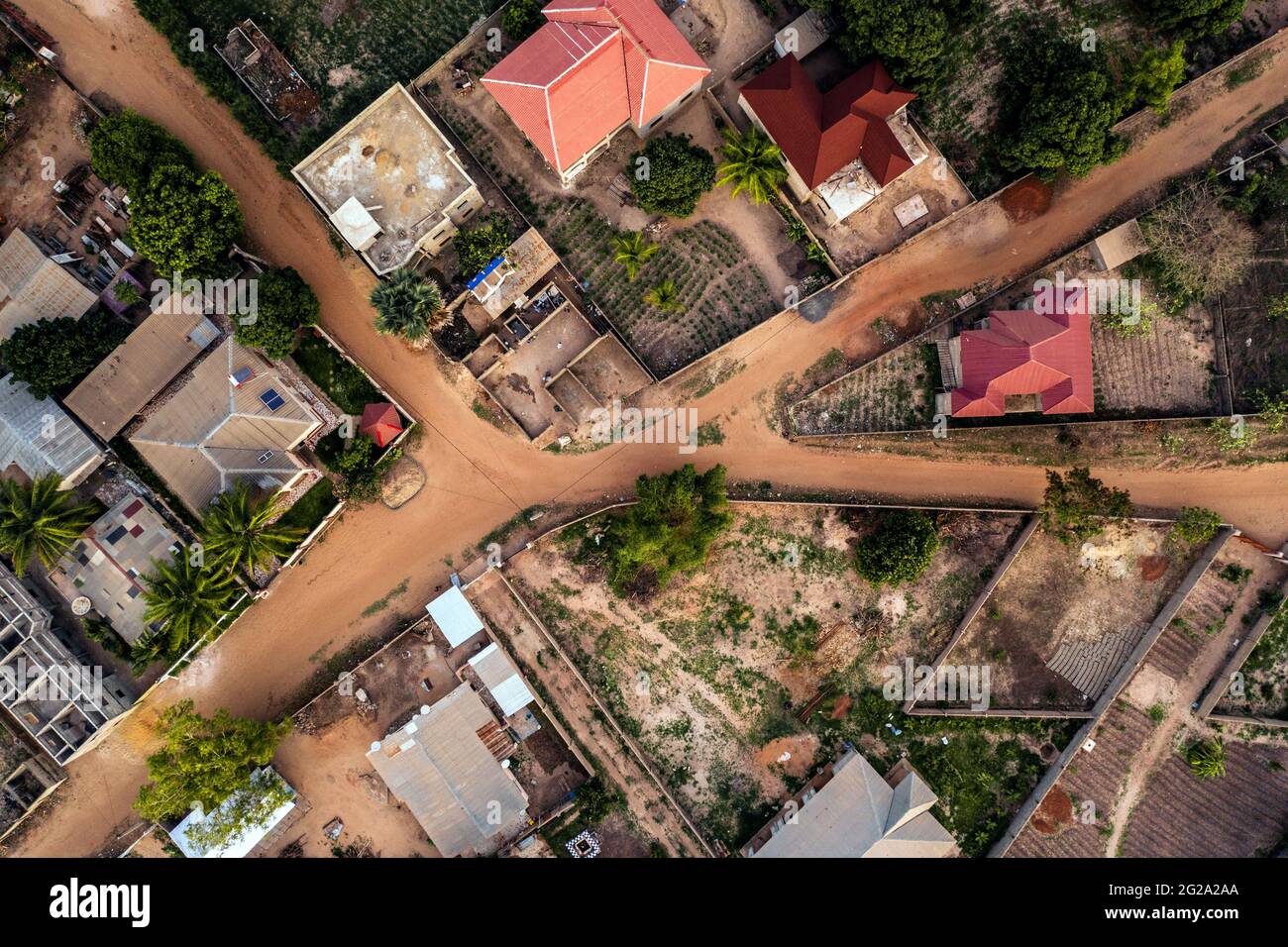Drohnenansicht von heruntergekommenen Häusern mit viel Grün und staubigen Straßen am Sommertag in Gambia, Afrika Stockfoto