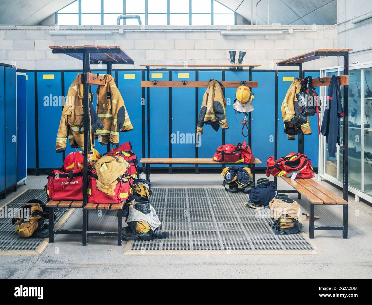 Leerer Umkleideraum in der Feuerwehr mit aufgehängten Uniformen und blauen Schließfächern Stockfoto