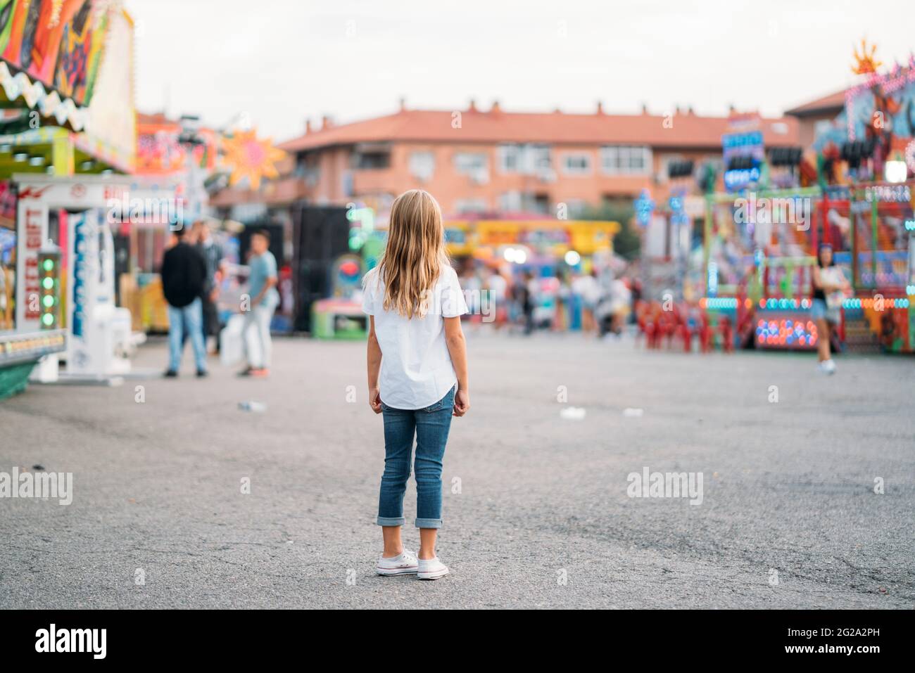 Rückansicht eines unerkennbaren kleinen Mädchens, das allein im Vergnügungspark steht Stockfoto