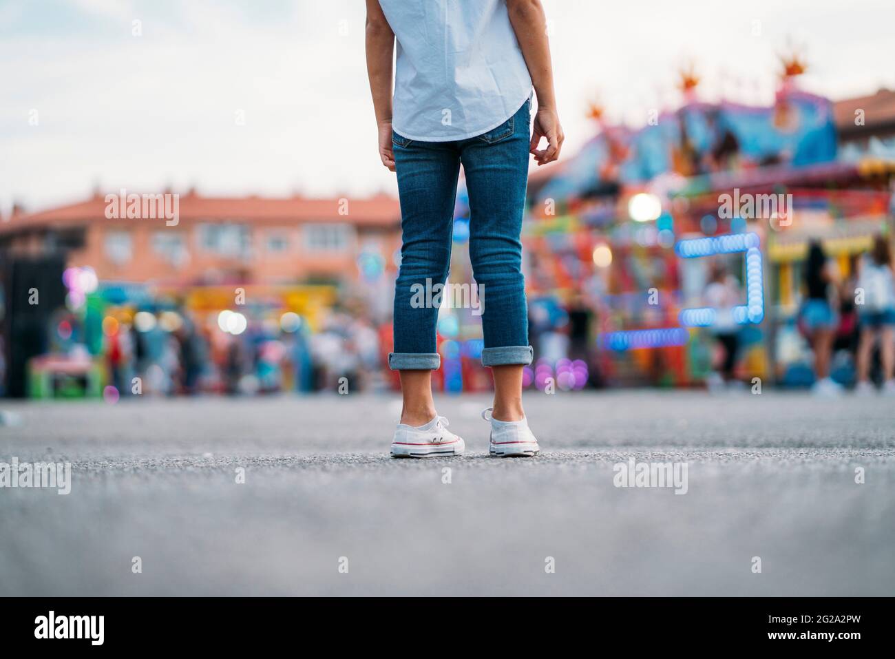 Rückansicht eines unerkennbaren kleinen Mädchens, das allein im Vergnügungspark steht Stockfoto