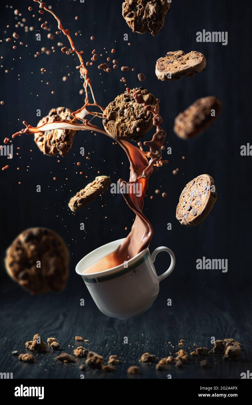 Kreative Studioaufnahme mit Plätzchen, die um einen Schokoladenbecher fliegen Stockfoto
