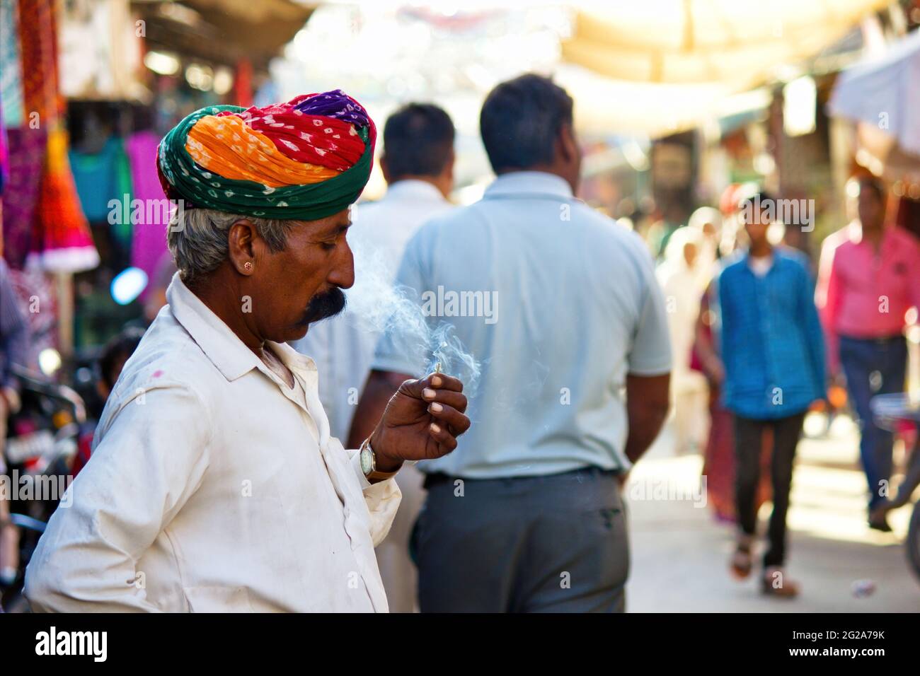 Pushkar, Indien - 10. NOVEMBER 2016: Ein alter Rajasthani-Mann in traditioneller ethnischer Kleidung wie buntem Turban und typischer weißer Hemdraucherzigarette Stockfoto