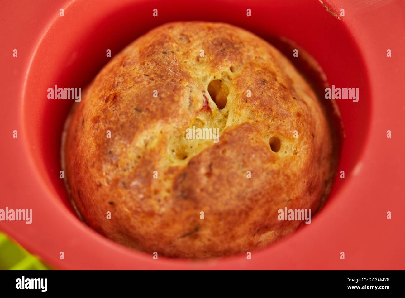 Gebackene Muffins mit sonnengetrockneten Tomaten in Silikonform nach dem Backen Stockfoto