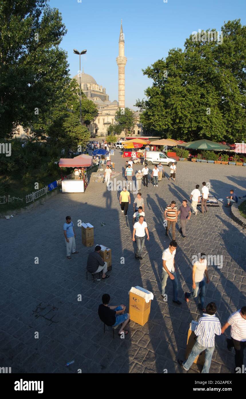 Istanbul, Türkei - 19. Juli 2010: Viele Menschen gehen durch einen Platz, der vom Minarett der Bayezid-Moschee in Istanbul dominiert wird, deren lange Schatten von La Stockfoto