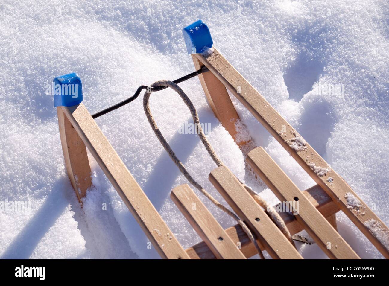 Nahaufnahme eines Holzschlittens, der an einem sonnigen Wintertag in reinem weißen Schnee steht. Gesehen in Deutschland im Februar. Stockfoto