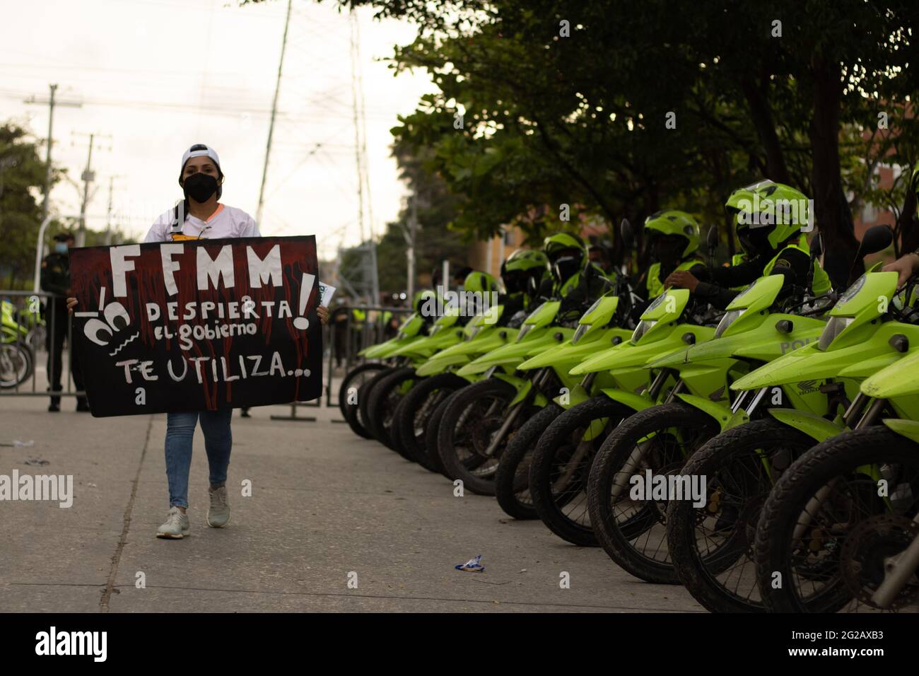 Eine Frau geht mit einem Anti-Polizei-Schild, auf dem steht: „Öffentliche Kräfte wachen auf! Die Regierung benutzt Sie, als die kolumbianischen und argentinischen Teams ein Qualifikationsspiel für die FIFA-Quatar-Weltmeisterschaft 2022 im Metropolitano Roberto Melendez-Stadion spielten, während die Demonstrationen um das Stadion eskalierten, um am 8. Juni 2021 in Barranquilla, Kolumbien, mit der kolumbianischen Bereitschaftspolizei gegen Unruhen und Polizeibrutalität zu kämpfen. Stockfoto