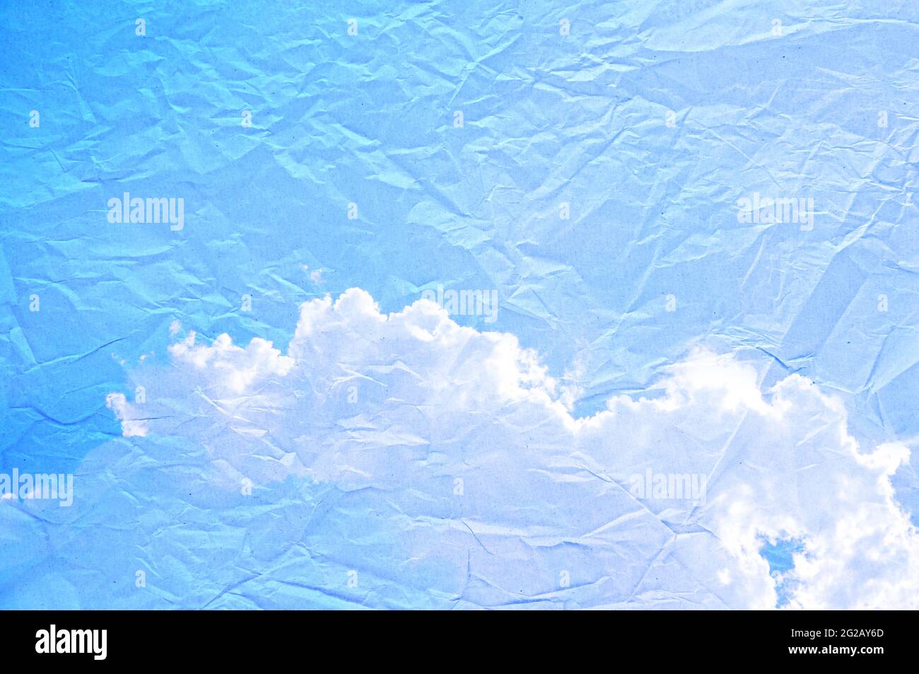 Blauer Himmel und Wolkenbild auf zerknittertem Papier Stockfoto