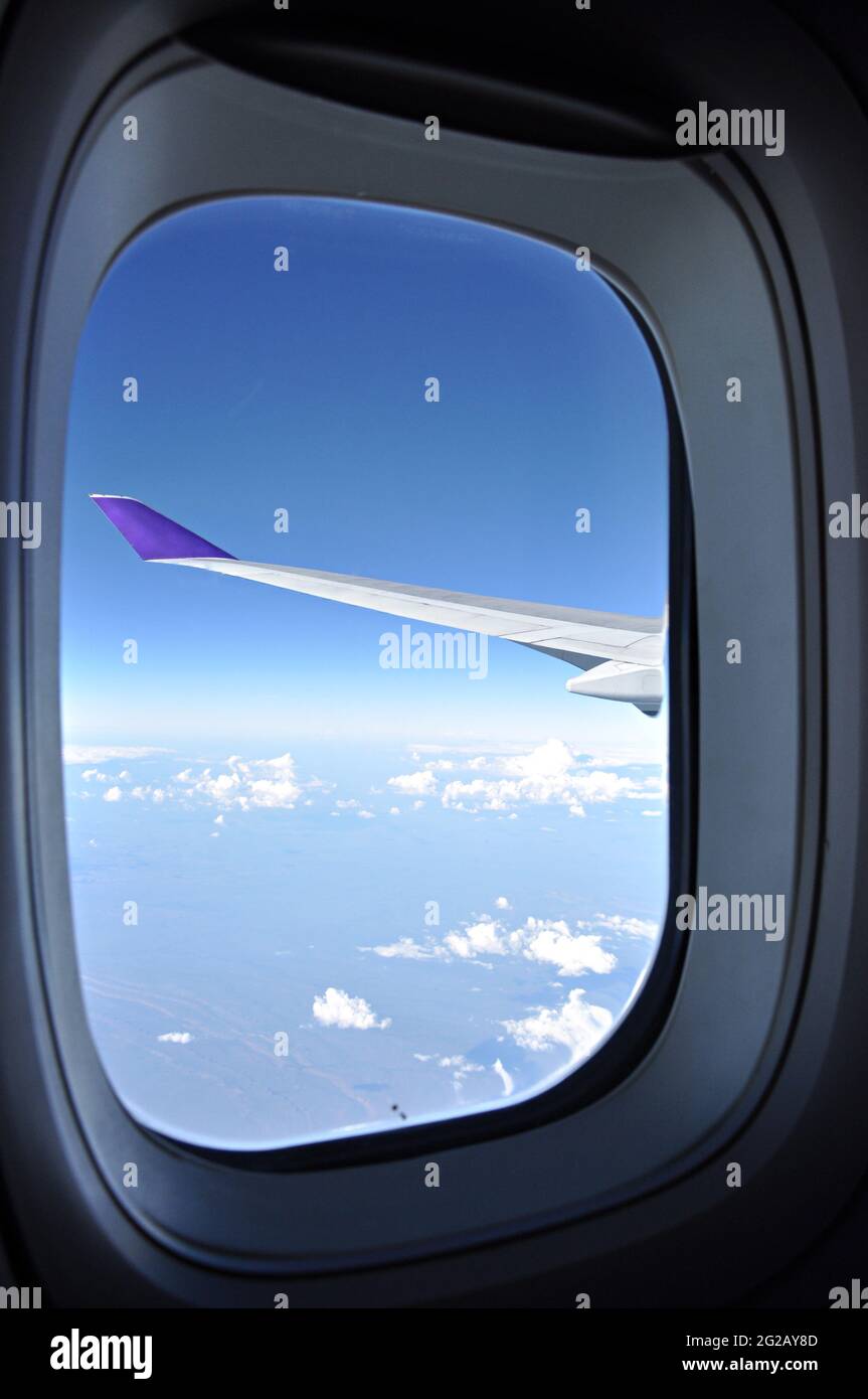 Blick auf die Erde und den blauen Himmel vom Fenster des Flugzeugs Stockfoto