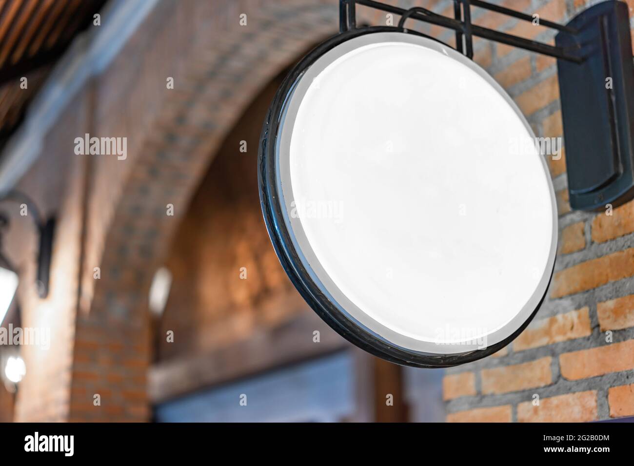 Der Circle White Lightbox hat an der Wand vor dem Backsteinpfosten in einem Tungsten Ambient Umgebung Vintage Shopping Community Mall gehängt. Stockfoto