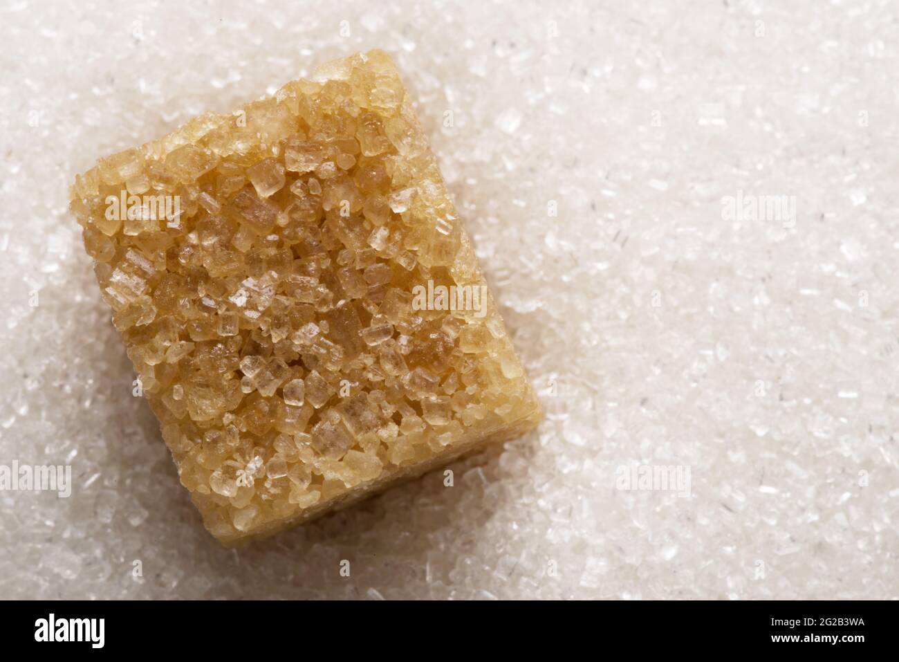 Weiße, raffinierte Zuckergranulate und brauner Zuckerwürfel darauf. Hintergrund der Speisen. Stockfoto