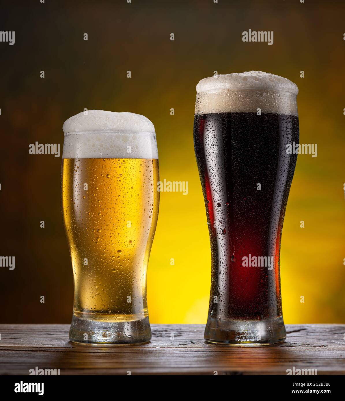 Gekühlte Gläser aus hellem und dunklem Bier mit Kondenswassertropfen auf dem Holztisch. Stockfoto