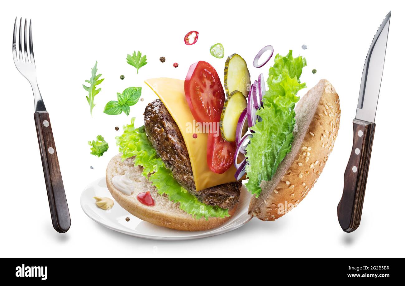 In der Luft hängen Cheeseburger-Zutaten und Essgeschirr. Konzeptbild von Fast Food. Datei enthält Beschneidungspfad. Stockfoto