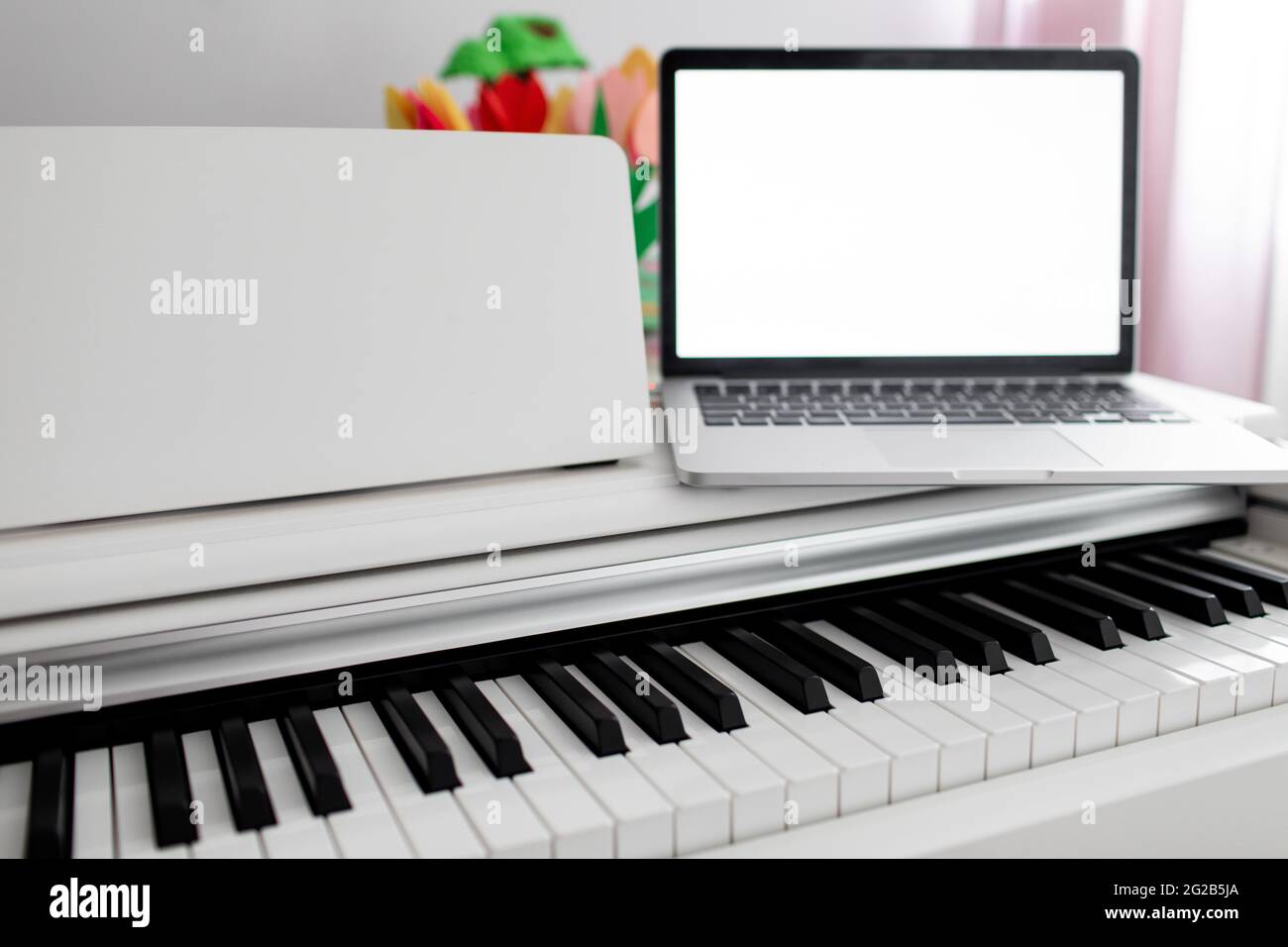 Ein weißes Klavier mit einem Laptop darauf. Fernschulung, Online-Bildung Stockfoto