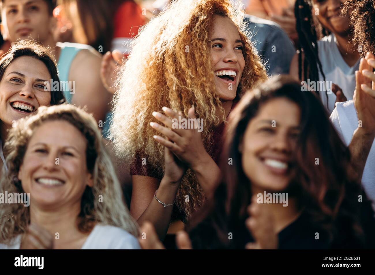 Frau, die ein Sportereignis beobachtet und klatscht. Begeisterter Sportfan, der applaudiert und den Sieg ihres Teams feiert. Stockfoto