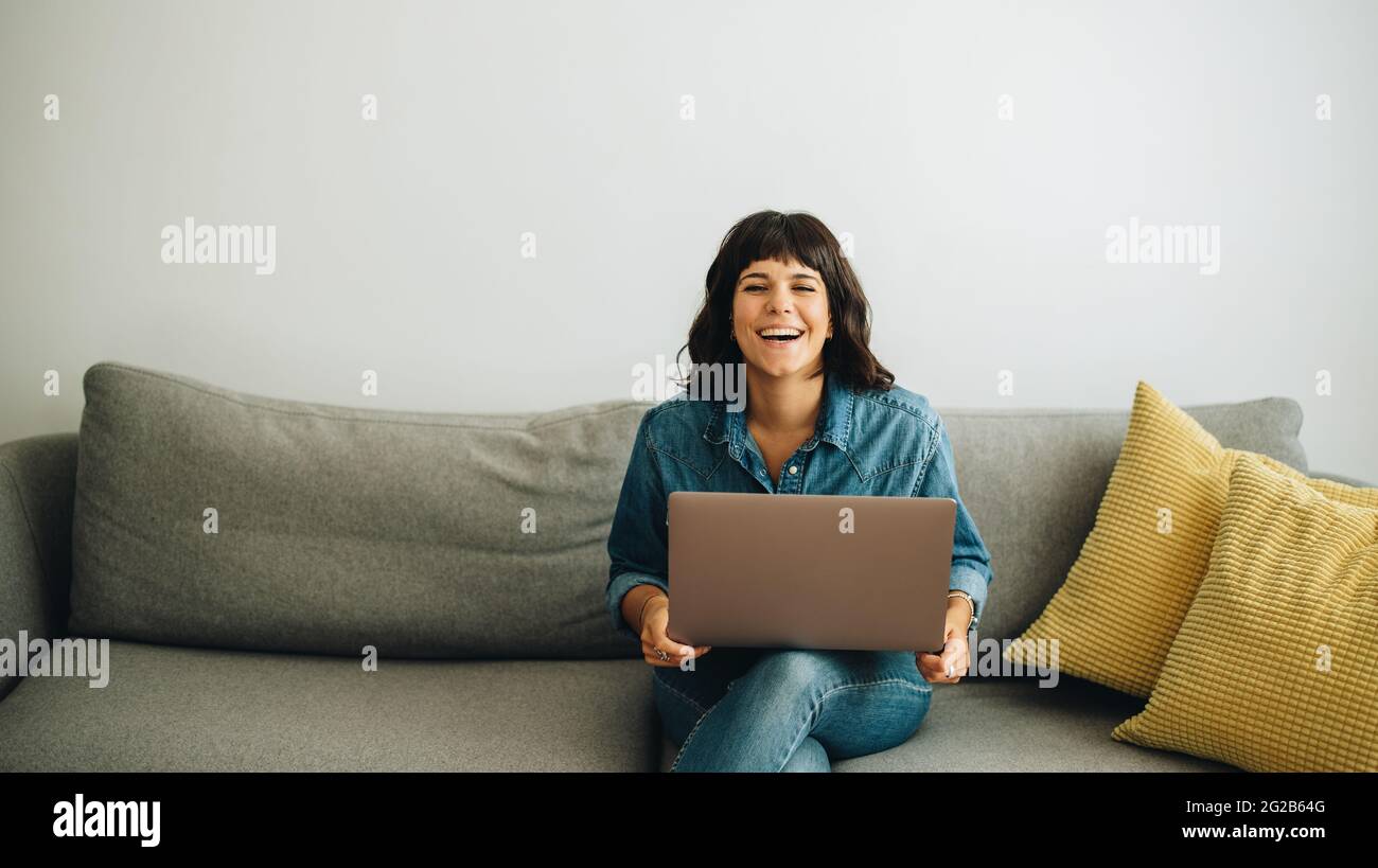 Geschäftsfrau mit Laptop in der Lobby. Fröhliche Geschäftsführerin, die einen Laptop auf dem Sofa benutzte. Stockfoto