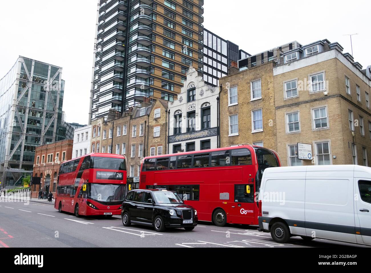 Blick auf 26 schwarze Taxis im Verkehr vor einer Reihe von Terrassen Principal Tower am Norton Folgate East London EC2 England UK KATHY DEWITT Stockfoto