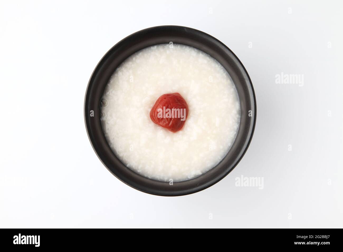 Reisbrei mit Salz eingelegten Pflaumen in einer Schüssel isoliert auf weißem Hintergrund Stockfoto