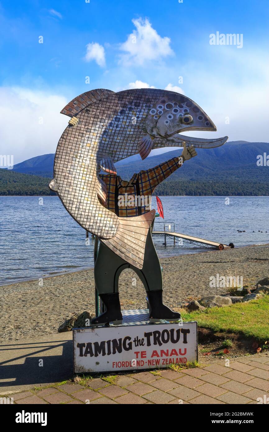 Ein Foto mit dem Titel „die Forelle zähmen“ am Ufer des Lake Te Anau, Neuseeland, zeigt einen Fischer, der einen riesigen Fisch in der Hand hält Stockfoto