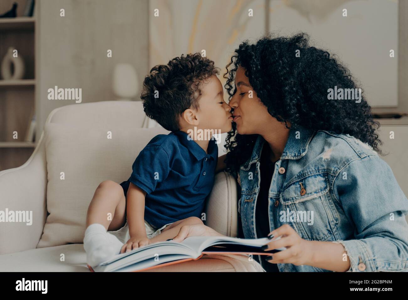 Glückliche gemischte Rasse junge Mutter mit kleinen Kind küssen sich gegenseitig, während die Zeit zusammen zu Hause verbringen Stockfoto