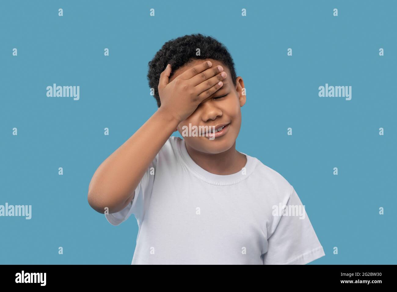 Unglücklicher Junge, der seine Stirn mit der Hand berührt Stockfoto