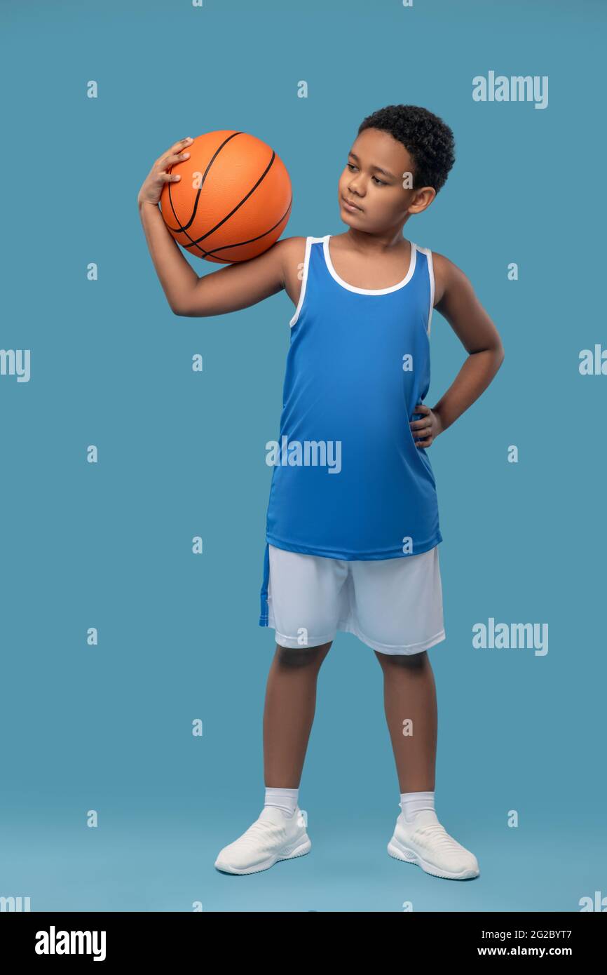 afroamerikanischer Junge in Sportbekleidung mit Basketballball Stockfoto