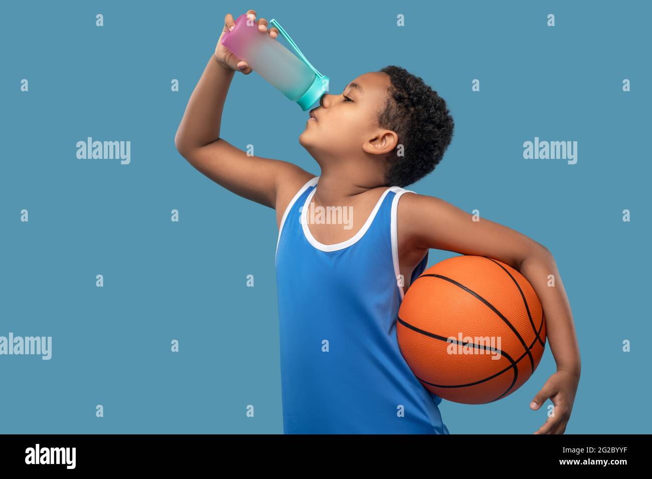 Junge mit Ball Trinkwasser aus Sportflasche Stockfoto