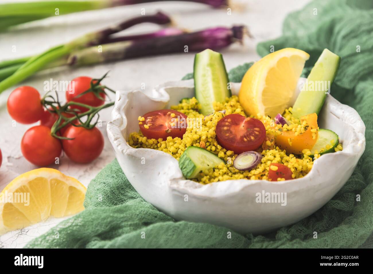 Couscous-Salat mit Gurken, Tomaten und Zwiebeln in einer weißen Schüssel Stockfoto