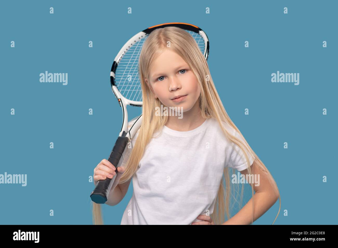Überselbstbewusstes Grundschulmädchen mit Tennisschläger Stockfoto