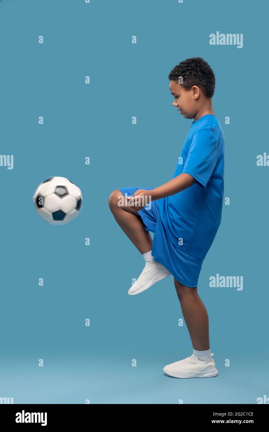 Profil von Jungen kneeing Fußball Stockfoto