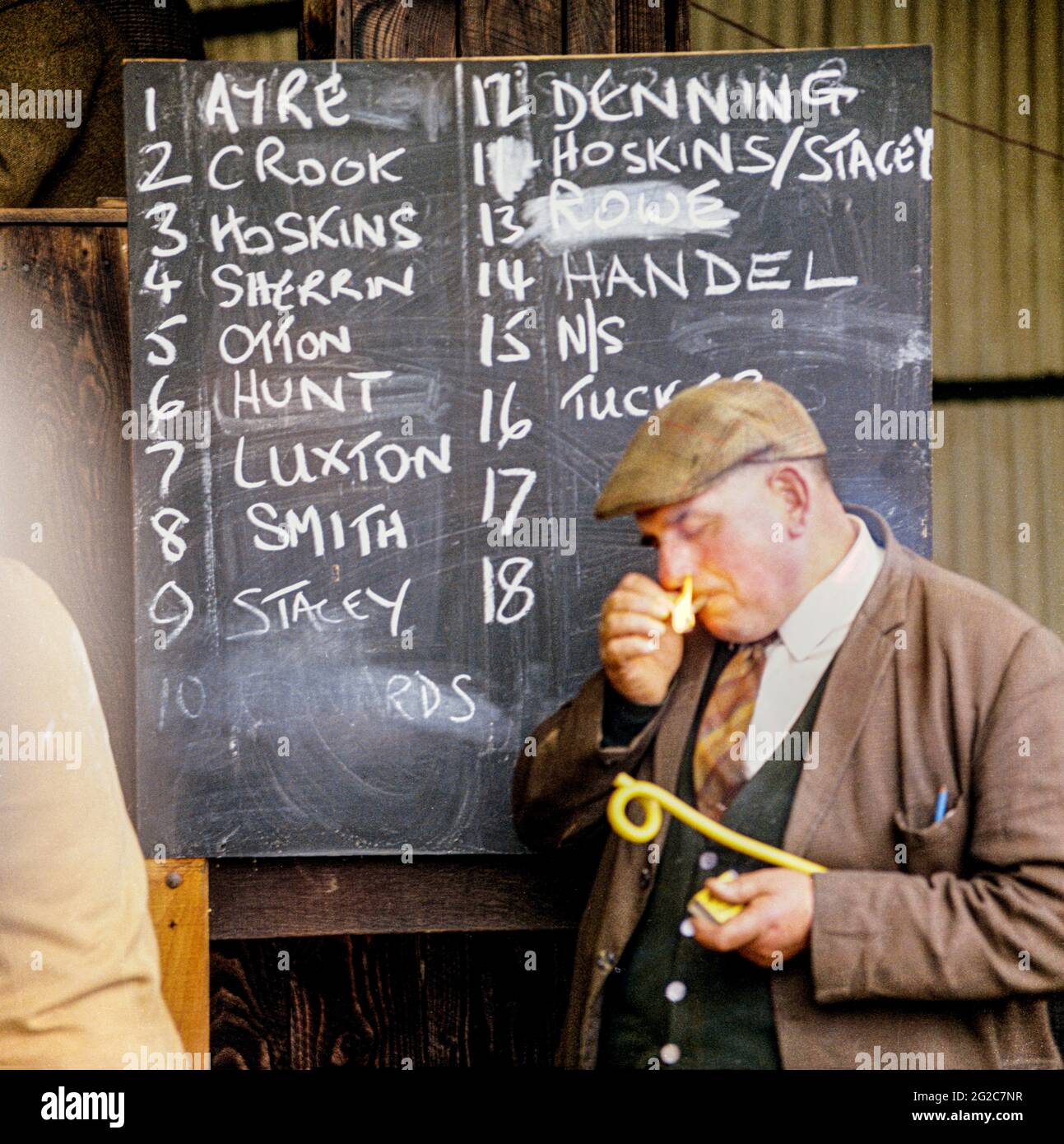 Ein Landwirt zündet im Oktober 1970 eine Zigarette vor einer Liste lokaler Exmoor-Bauern auf einer Tafel auf dem Exford Market, Somerset, Großbritannien, an Stockfoto