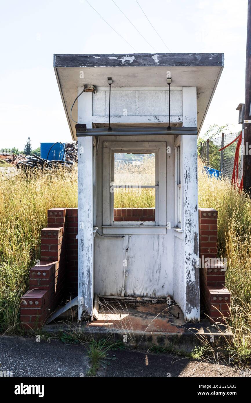 ELKIN, NC, USA-5 JUNE 2021: Kleines Sicherheitstor-Haus, jetzt verlassen, in altem Industriegelände. Vertikales Bild. Stockfoto