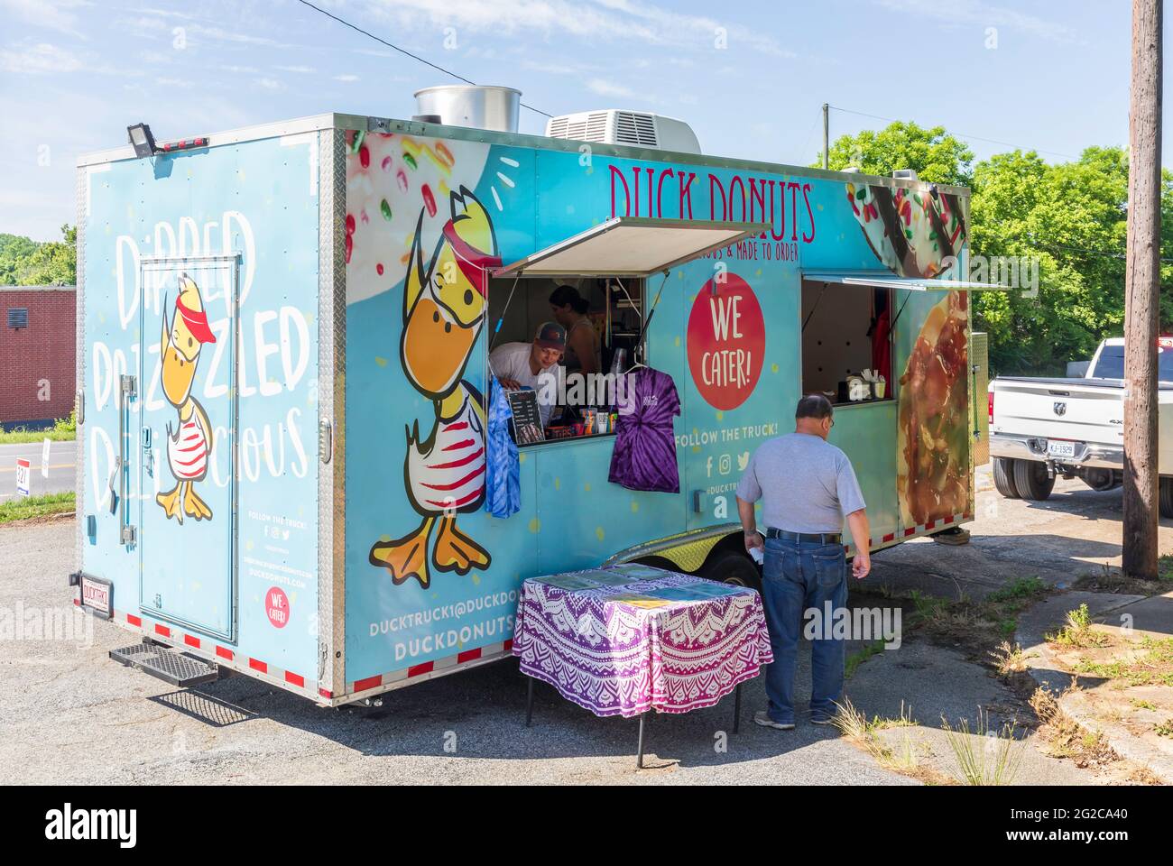 ELKIN, NC, USA-5 JUNE 2021: Ein mobiler Donut-Anbieter-Trailer namens 'Duck Donuts', mit einem Kunden. 3 Personen. Horizontales Bild. Stockfoto
