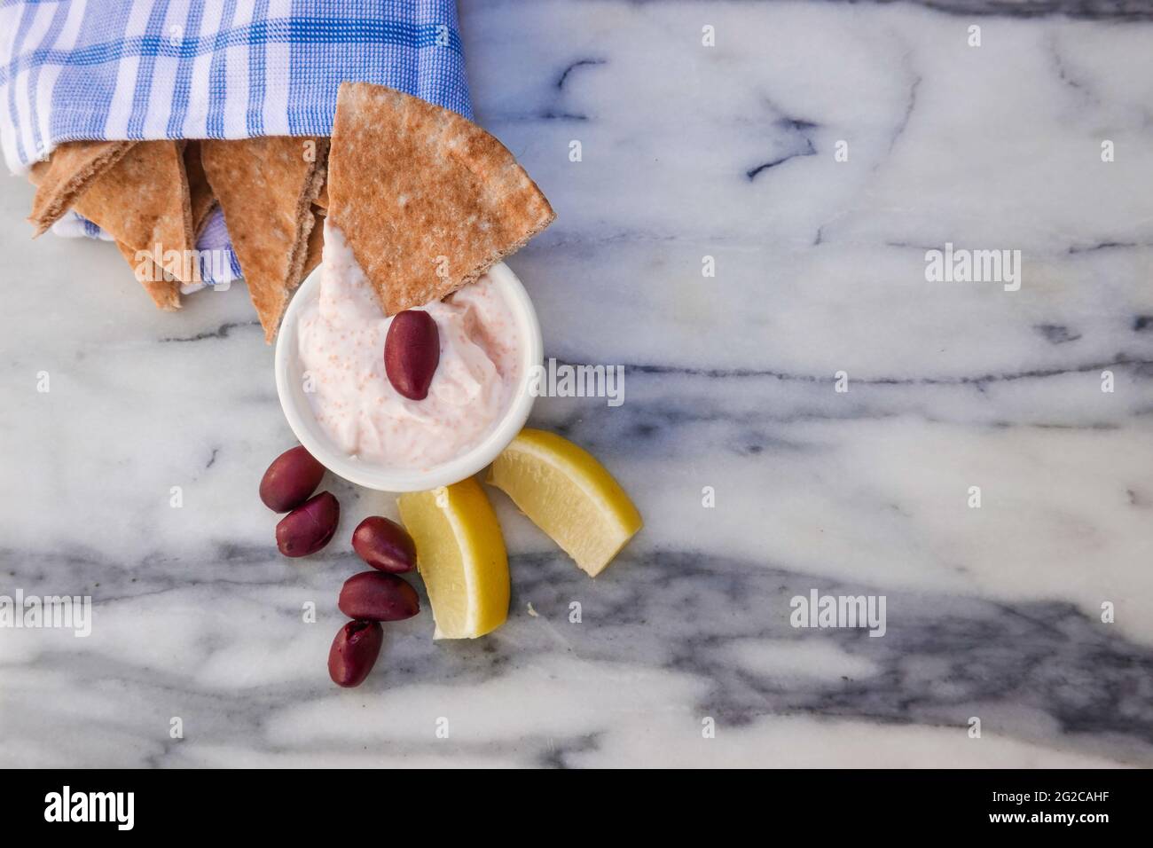 Taramosalata Pita-Brot, kalamata-Oliven und Zitronenkeile auf einer Marmorplatte. Stockfoto