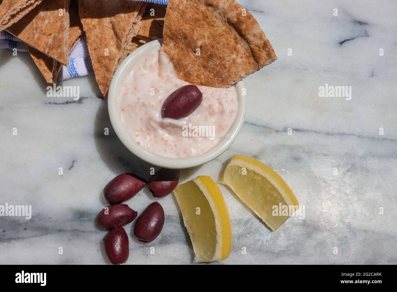 Taramosalata Pita-Brot, kalamata-Oliven und Zitronenkeile auf einer Marmorplatte. Stockfoto