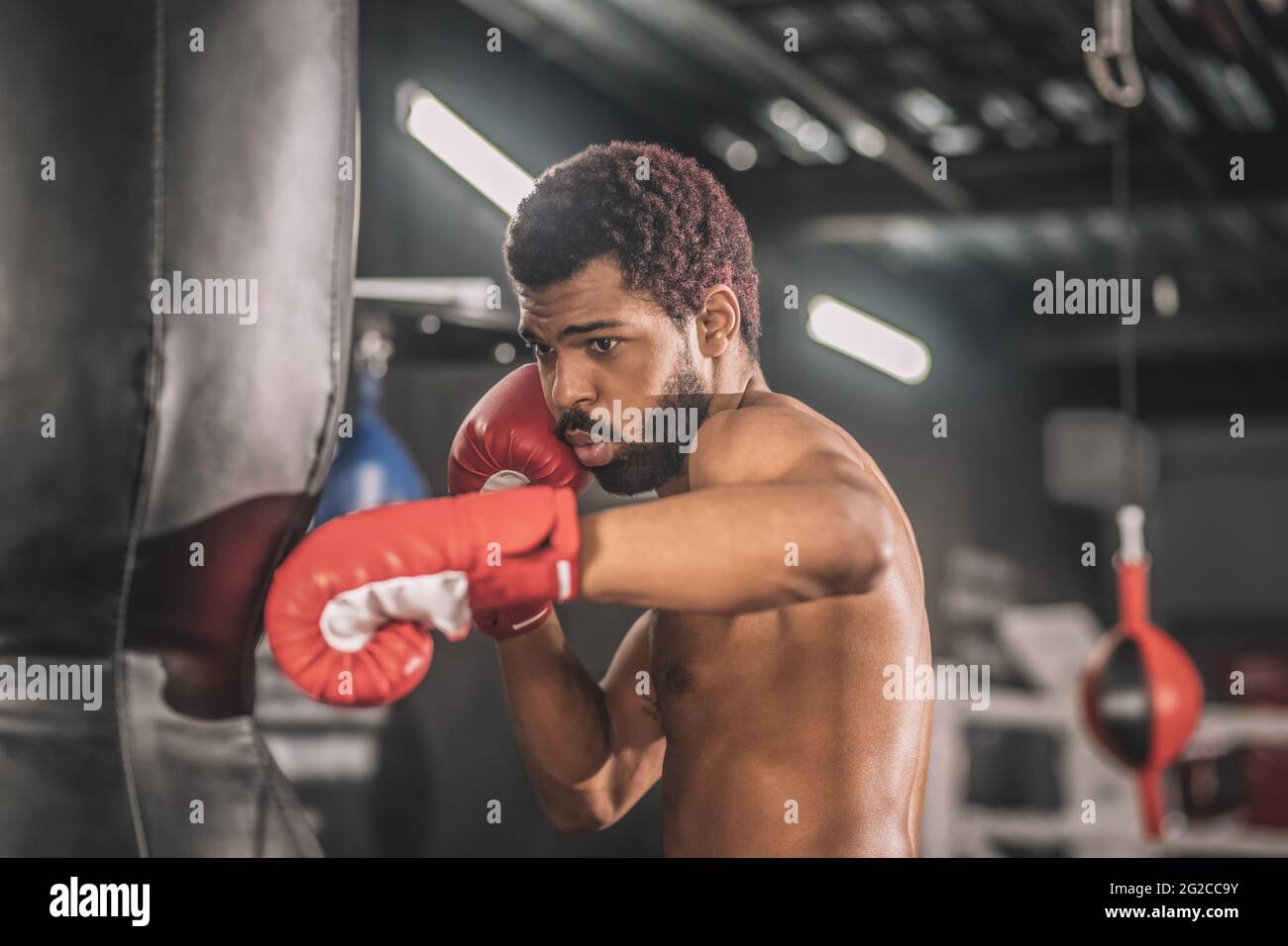 Junge dunkelhäutige Boxerin, die in einem Fitnessstudio trainiert Stockfoto