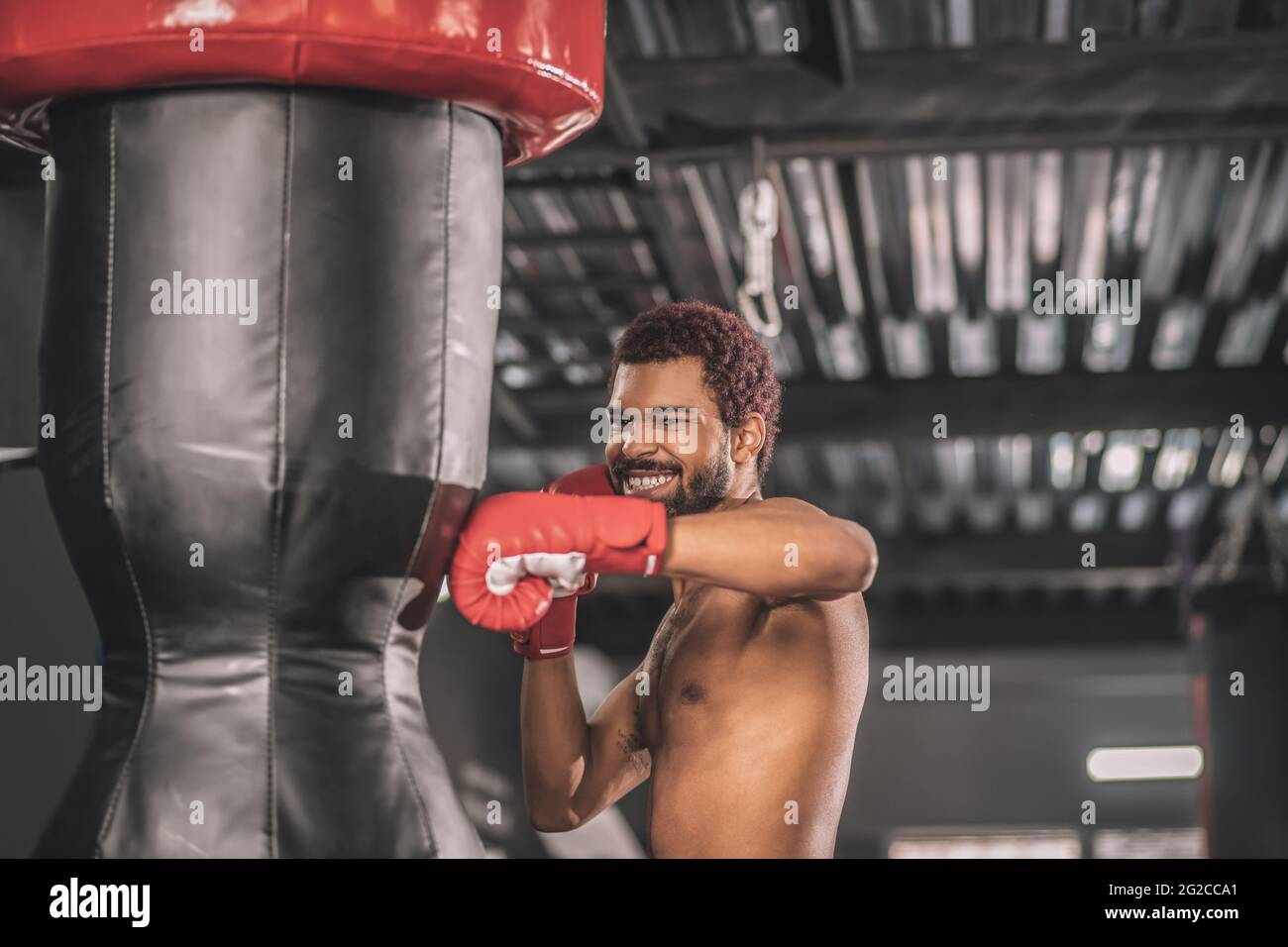 Junge dunkelhäutige Boxerin, die in einem Fitnessstudio trainiert Stockfoto